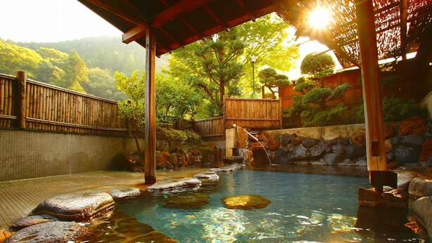 A traditional Japanese onsen with a wooden deck, stone steps, and a bamboo fence. - Gensenkakenagashi No Yu Onyado Sakaya (Shizuoka)