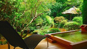 A wooden deck with a chair, a hot tub, and lush greenery. - Gensenkakenagashi No Yu Onyado Sakaya (Shizuoka)