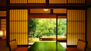 A traditional Japanese room with tatami flooring, sliding doors, and a view of a lush garden. - Gensenkakenagashi No Yu Onyado Sakaya (Shizuoka)