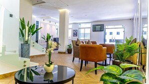 A modern lobby with a glass staircase, comfortable seating, and indoor plants. - Hotel Les Ambassadeurs (Casablanca)