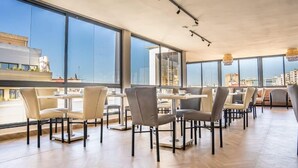A modern dining area with large windows, tables, and chairs arranged for guests. - Hotel Les Ambassadeurs (Casablanca)