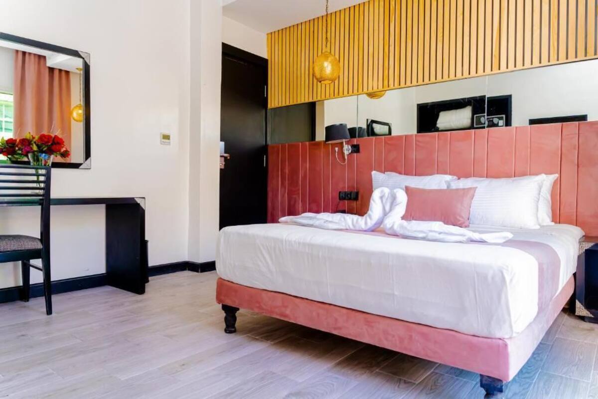 Una habitación de hotel con una cama grande, un escritorio y un espejo.