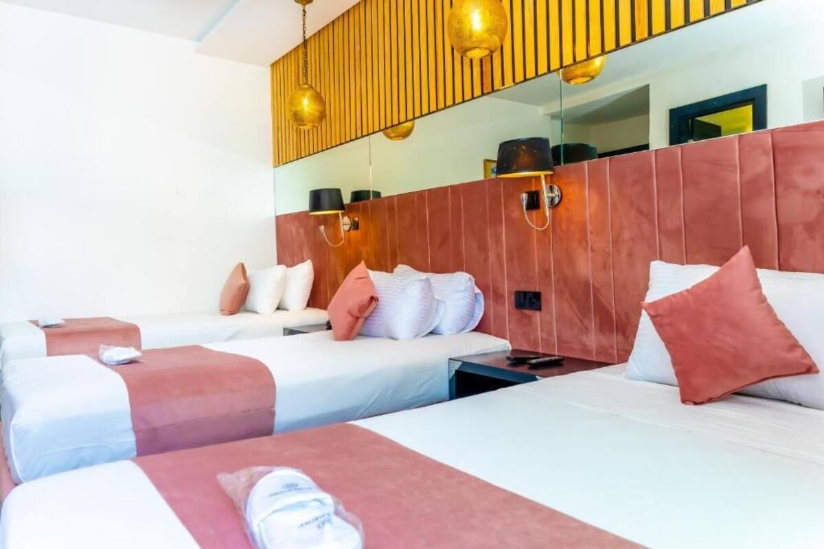 Habitación de hotel con dos camas, un espejo grande y un cabecero de madera.