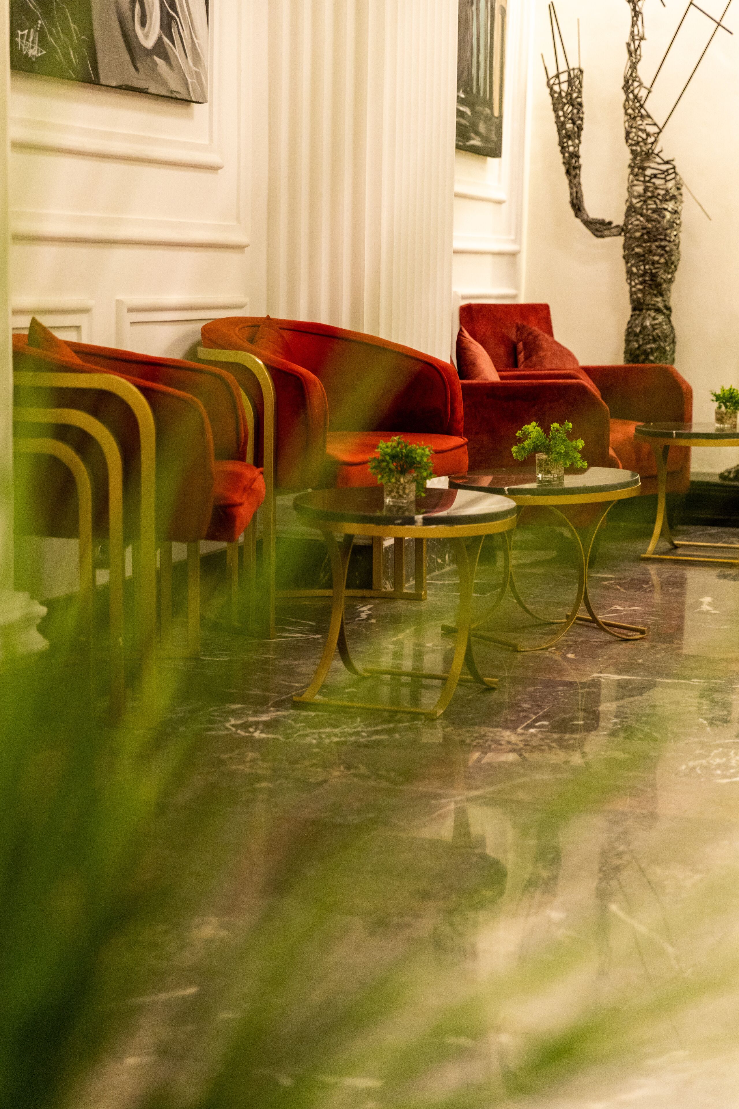 A modern living room with red sofas, a glass coffee table, and a decorative tree sculpture.
