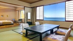A room with tatami mats, a bed, a table with chairs, and a view of the sea. - Yaizu Grand Hotel (Shizuoka)