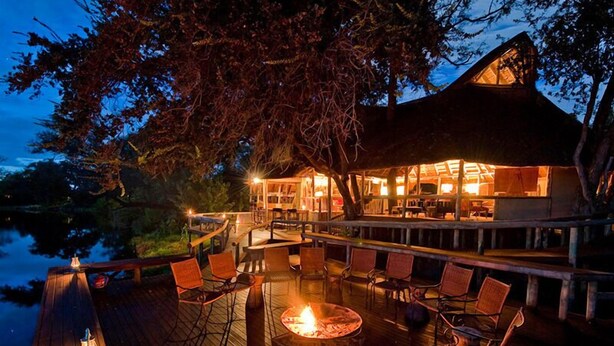An outdoor dining area with a fire pit, wooden deck, and seating.