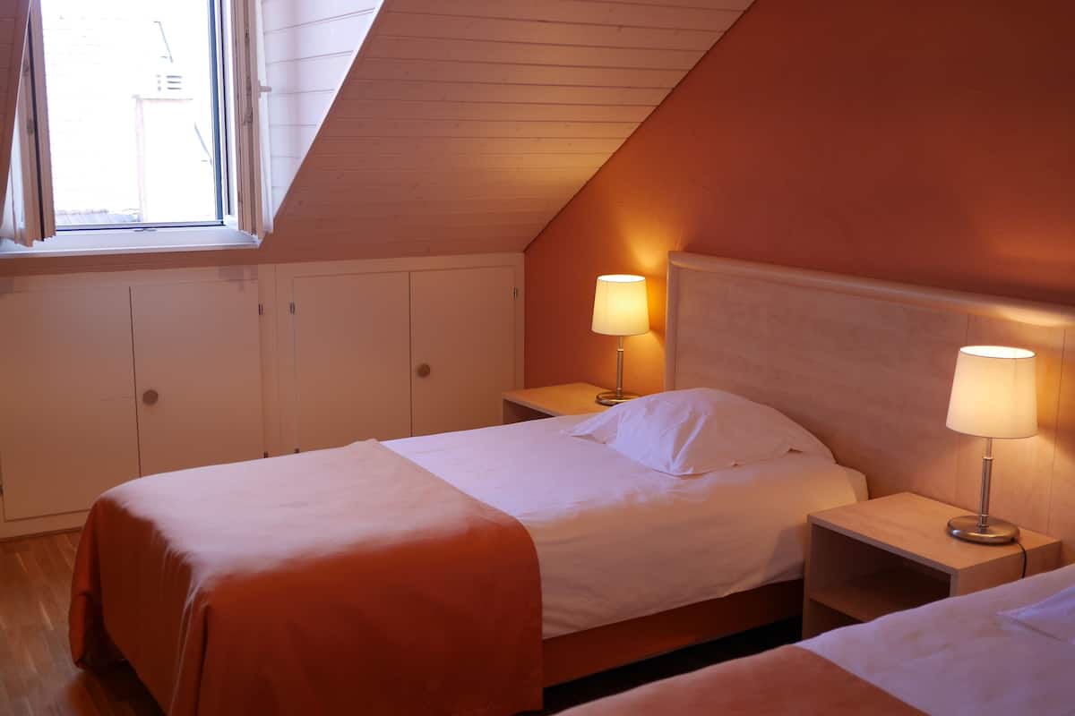 A bedroom with two beds, wooden headboards, and bedside lamps.