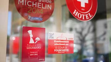 A close-up of various signs, including a Michelin guide selection sign, a passport gourmet partner sign, and a hotel sign.