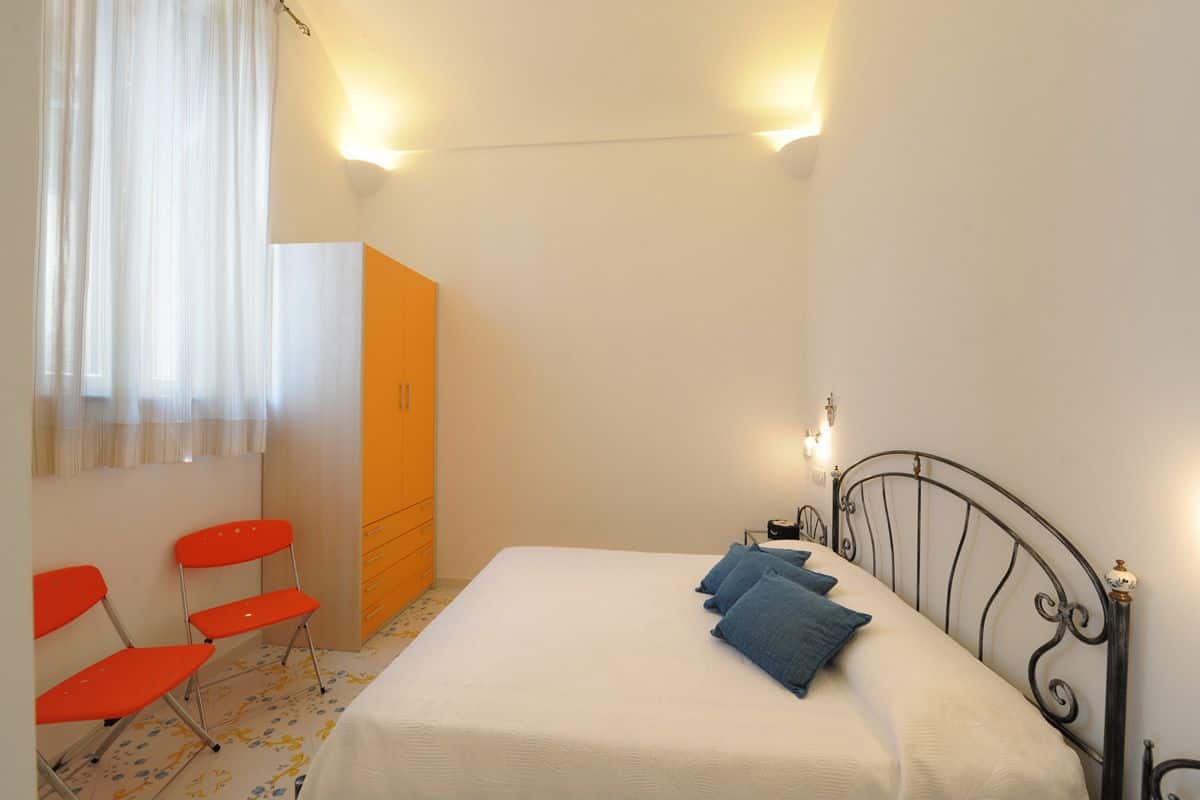 Un dormitorio con cama, armario y dos sillas.