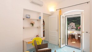 Una habitación con escritorio, silla, estanterías y un balcón con mesa y sillas.