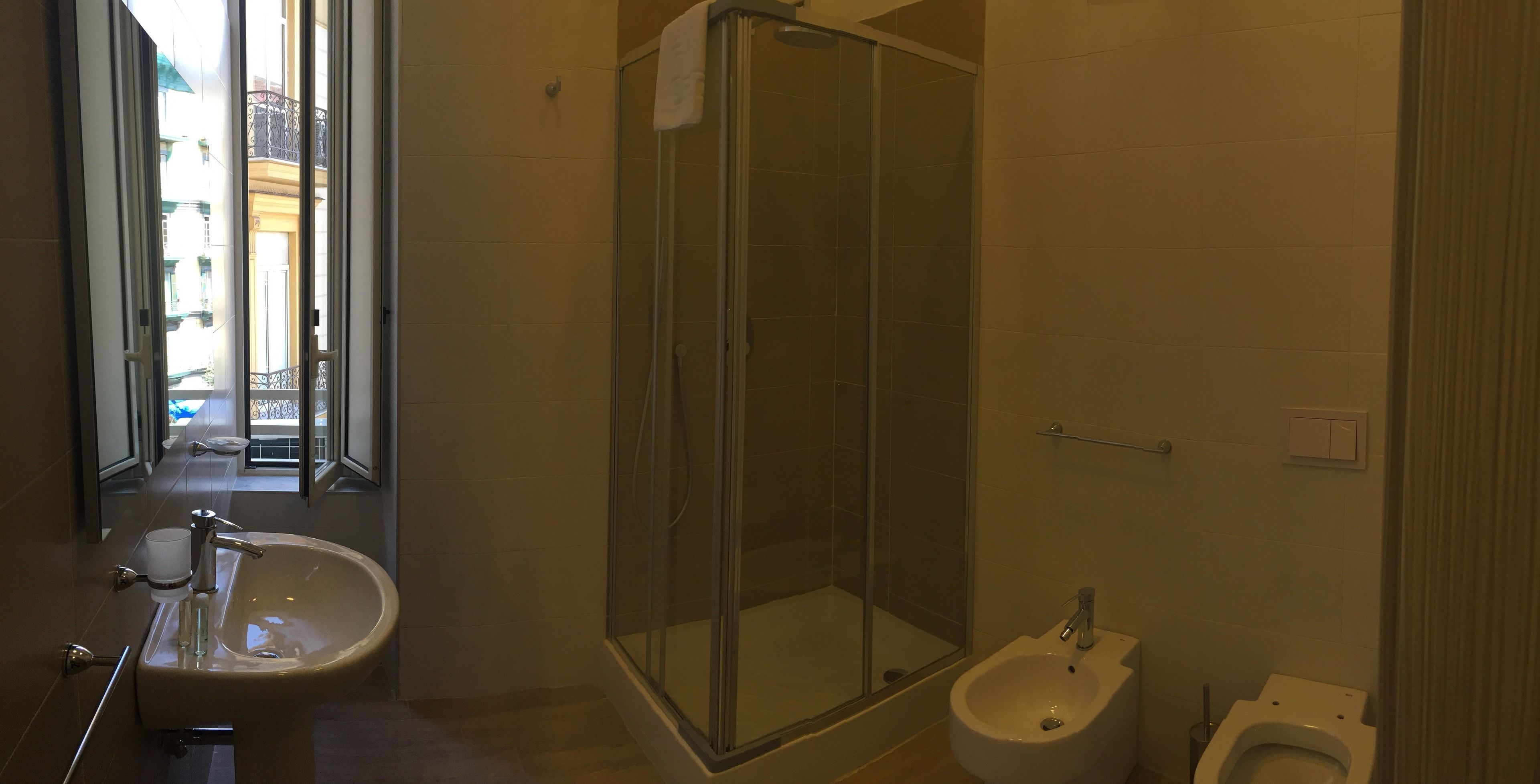 A bathroom with a glass-enclosed shower, a bidet, and a sink.
