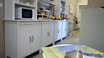 Una cocina con armarios blancos, un microondas y diversos objetos de cocina sobre las encimeras.