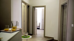 Un pasillo con una zona de cocina a la izquierda, una mesa de comedor con un vaso y vistas a otra habitación.