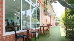 Un espace patio agrémenté d’un mur en briques, de grandes fenêtres et d’une petite table avec des chaises.