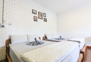 A hotel room with two beds, white brick walls, and framed pictures on the wall.