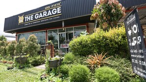 Un restaurant appelé «
The Garage
», avec une enseigne et un espace jardin à l’avant.
