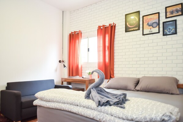 A bedroom with a bed, a desk, a chair, and a window with curtains.