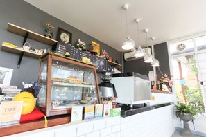 A cafe with a chalkboard menu, a coffee machine, and shelves with various items.