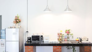 Une cuisine équipée d’un réfrigérateur, d’un four à micro-ondes et d’un évier. Deux luminaires suspendus sont fixés au-dessus du plan de travail.