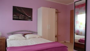 A bedroom with a bed, a wardrobe, a night cityscape painting, and a mirror reflecting a bed. - Gästezimmer Vogelsberg (Freiensteinau)