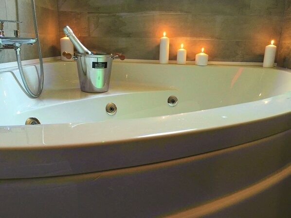 A bathtub with candles and a bucket.