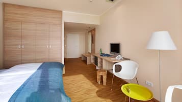 Ein Hotelzimmer mit einem Bett, einem Schreibtisch mit Computer, einem Stuhl und einer Lampe.