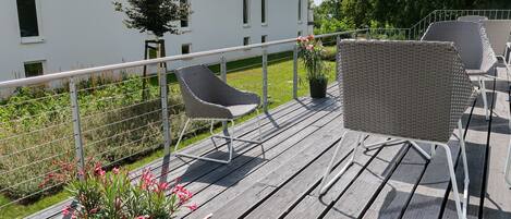 Une terrasse en bois avec des chaises en osier et une plante en pot.