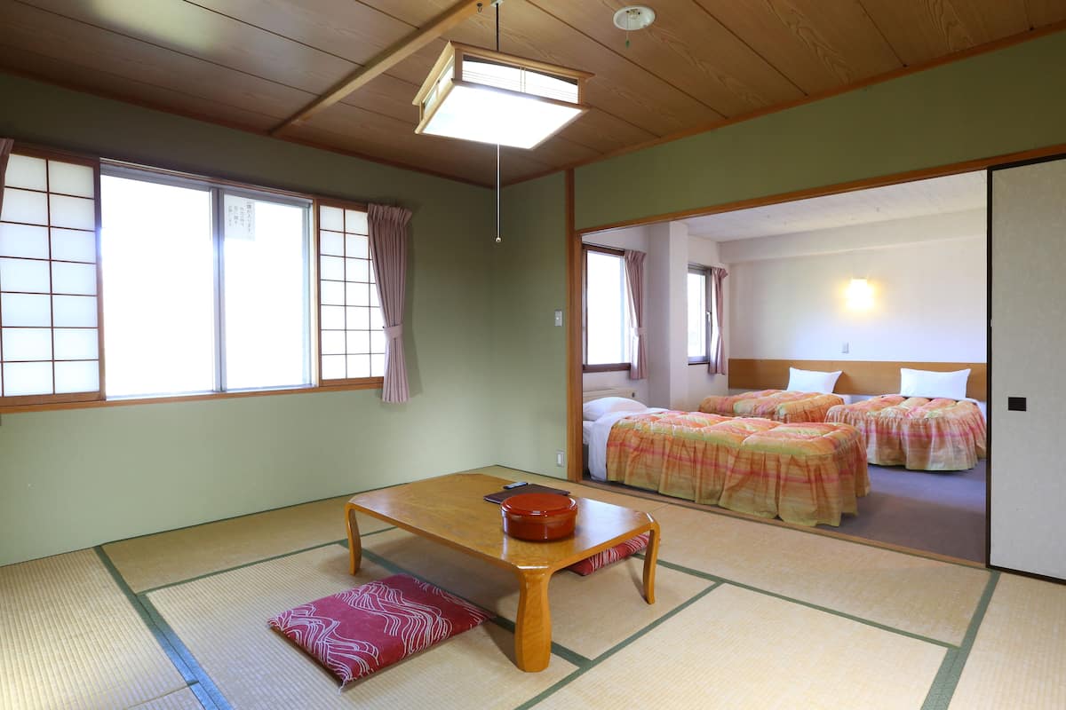 A traditional Japanese room with tatami flooring, a low wooden table, and a futon bed set.