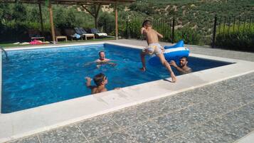 Een buitenzwembad, ligstoelen bij het zwembad