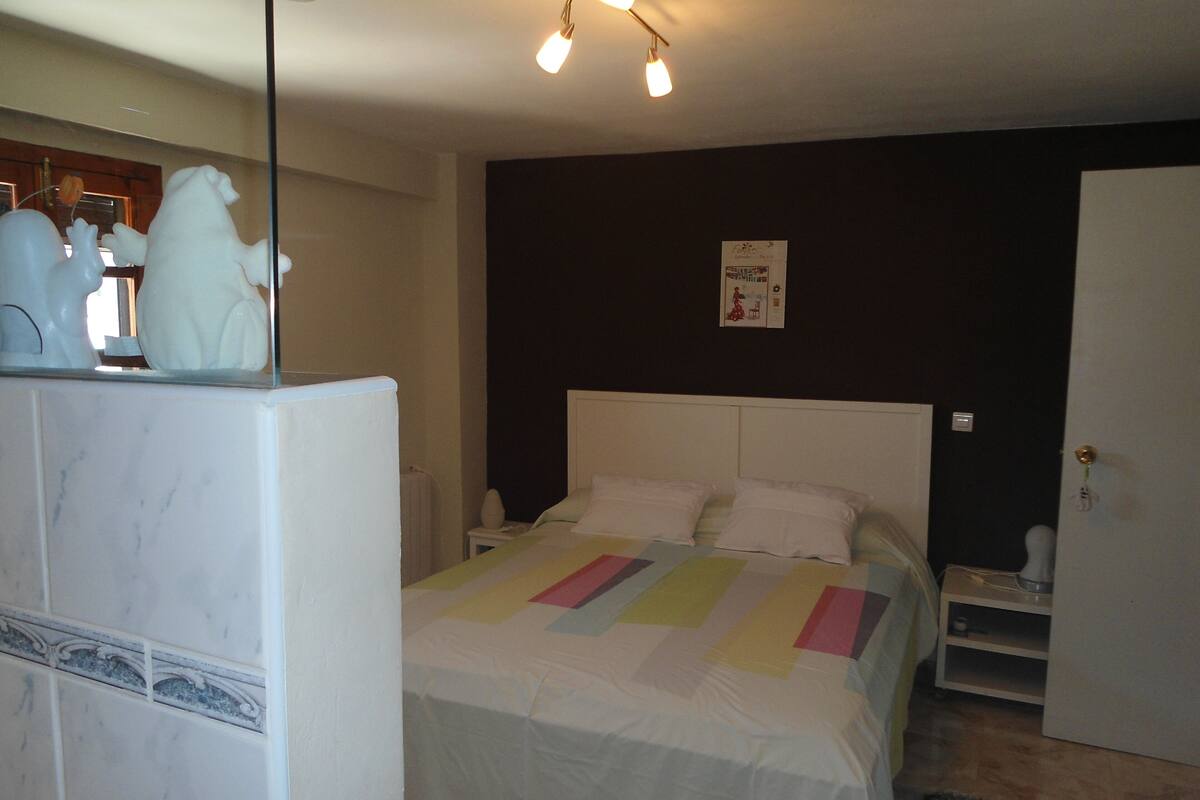 Ein Schlafzimmer mit einem Bett, einem Nachttisch, einer Kommode und einer Wand mit einem Poster.