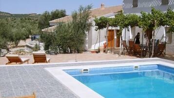 Una piscina al aire libre, sillones reclinables de piscina