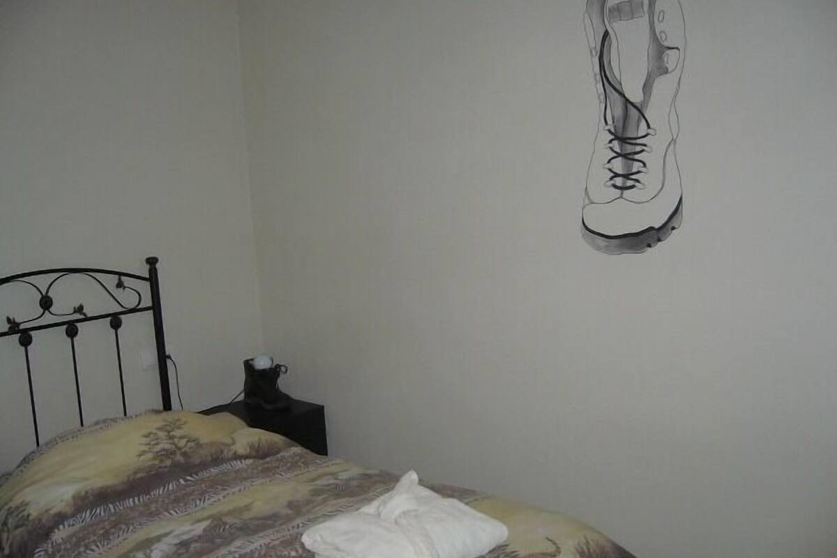 Ein Schlafzimmer mit einem Bett, einem Nachttisch und einem an der Wand befestigten Schuhregal.