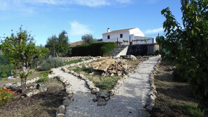 A garden pathway leading to a white house with a tiled roof, surrounded by greenery and rocks. - Lasnavillasmm (Montefrio)