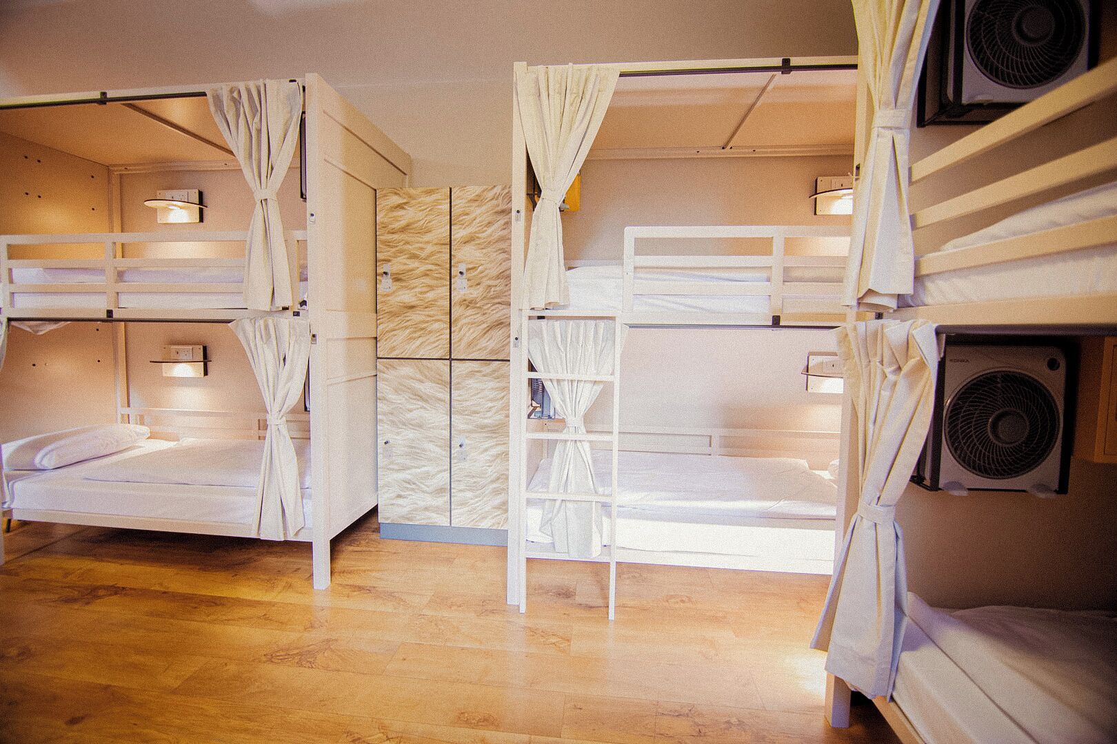 A room with bunk beds, a wooden floor, and a wall-mounted air conditioning unit.