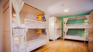 Des lits superposés avec des compartiments de rangement, un ventilateur de plafond et un mur vert.