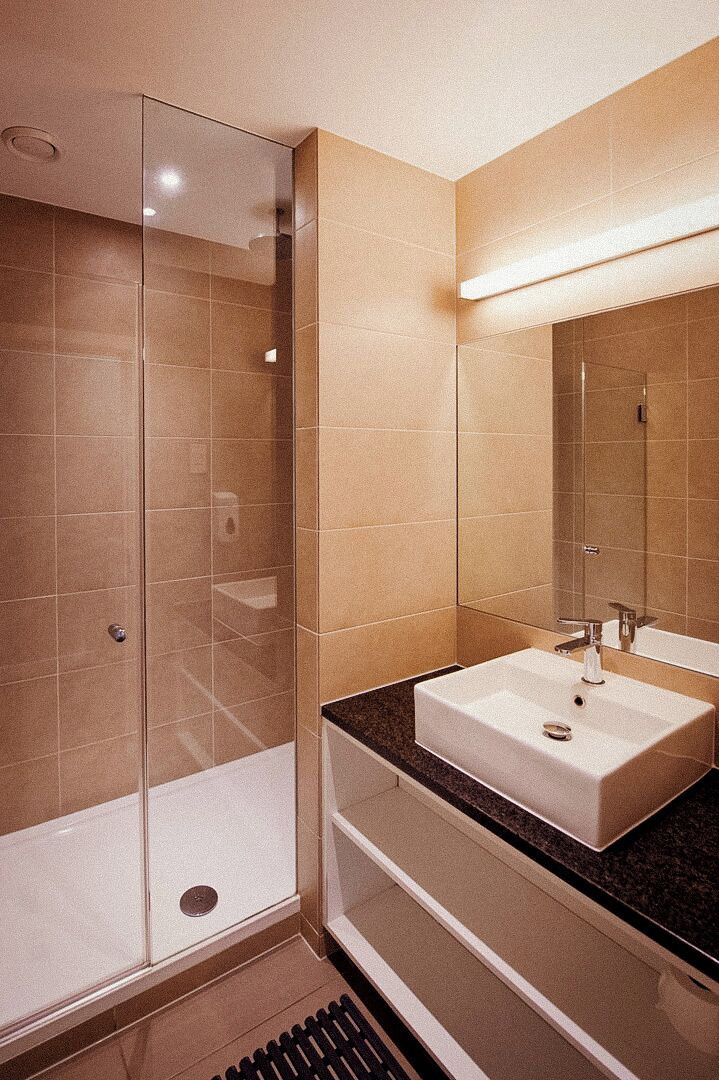 Une salle de bain moderne avec une douche à parois de verre, un lavabo blanc et un grand miroir.