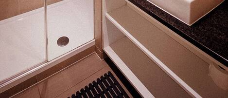Une salle de bain moderne avec une douche à parois de verre, un lavabo blanc et un grand miroir.