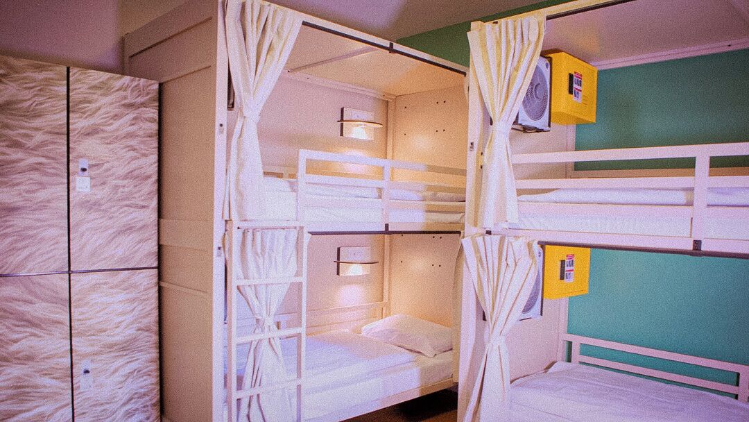 Bunk beds with curtains, a fan, and a small box on the wall.