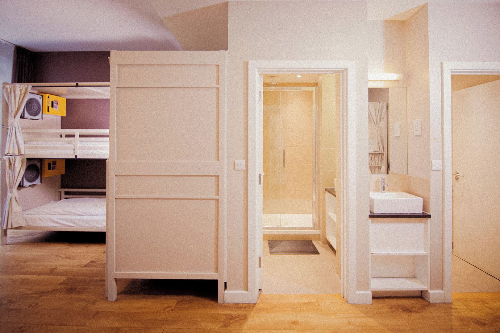 Een kamer met stapelbedden, een badkamer met wastafel en douche.