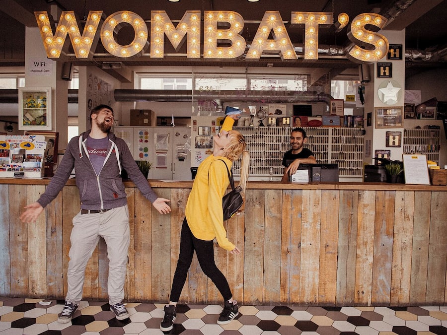 A reception area with a wooden counter, a sign reading 'WOMBAT'S', and a person standing behind the counter.