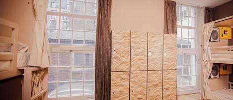 A room with a bunk bed, a wardrobe, and a window with curtains.