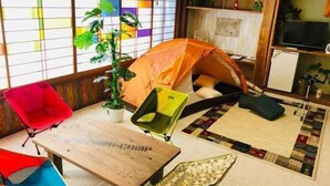 Una habitación acogedora con una tienda de campaña, una mesita, una silla y una planta en maceta.