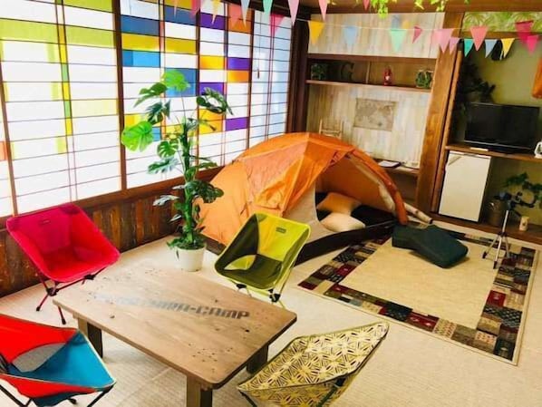 Ein gemütliches Zimmer mit Zelt, einem kleinen Tisch, einem Sessel und einem Blumentopf.