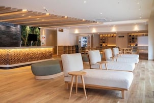 Un moderno vestíbulo de hotel con mostrador de recepción, zona de estar y una escalera.