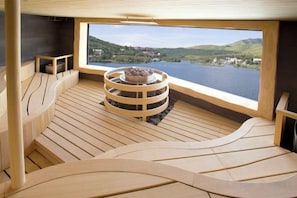 Een houten terras met een zithoek in een cirkelvorm en uitzicht op een meer.