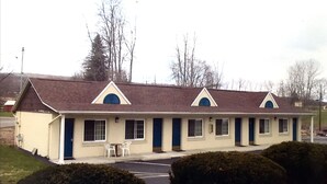 A motel with a row of rooms, each with a small porch and a single chair. - Economy Inn Ithaca (Ithaca)
