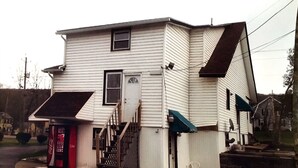 A two-story house with a front porch, a Coca-Cola vending machine, and a small staircase leading to the entrance. - Economy Inn Ithaca (Ithaca)