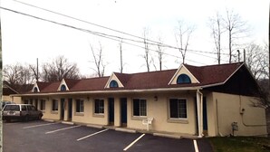 A motel with a row of rooms, a parking lot, and a single-story building with a brown roof. - Economy Inn Ithaca (Ithaca)