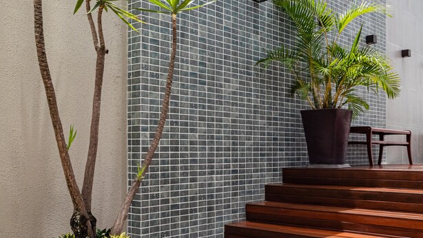 A modern building with a tiled wall, wooden steps, and potted plants. - Citi Hotel Residence (Caruaru)