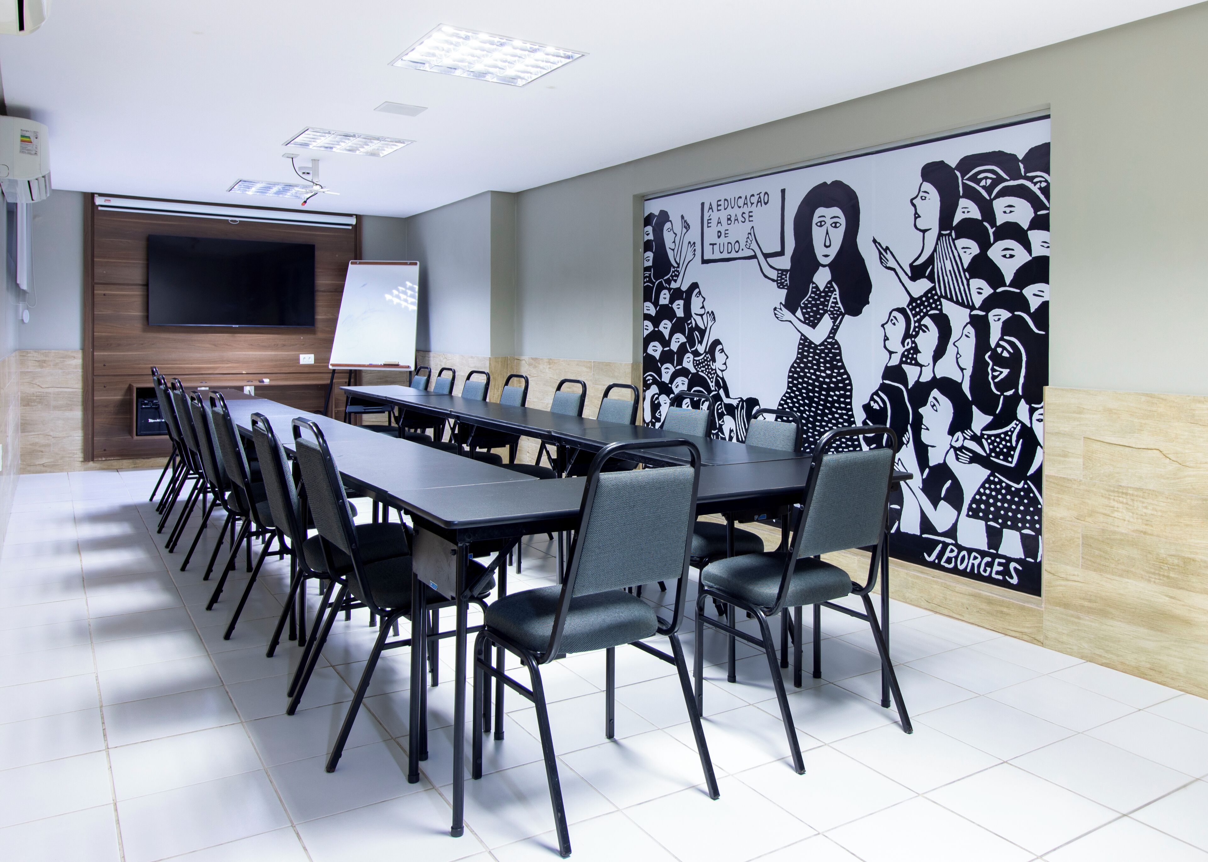 Un salón de conferencias con una larga mesa, sillas, una pizarra y un gran mural en la pared.